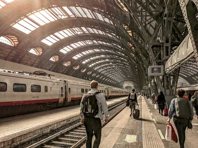 People walking inside of Milano Centrale Station in Milan, Italy - one of the best ways to get to Milan is by train if you are spending one day in Milan.