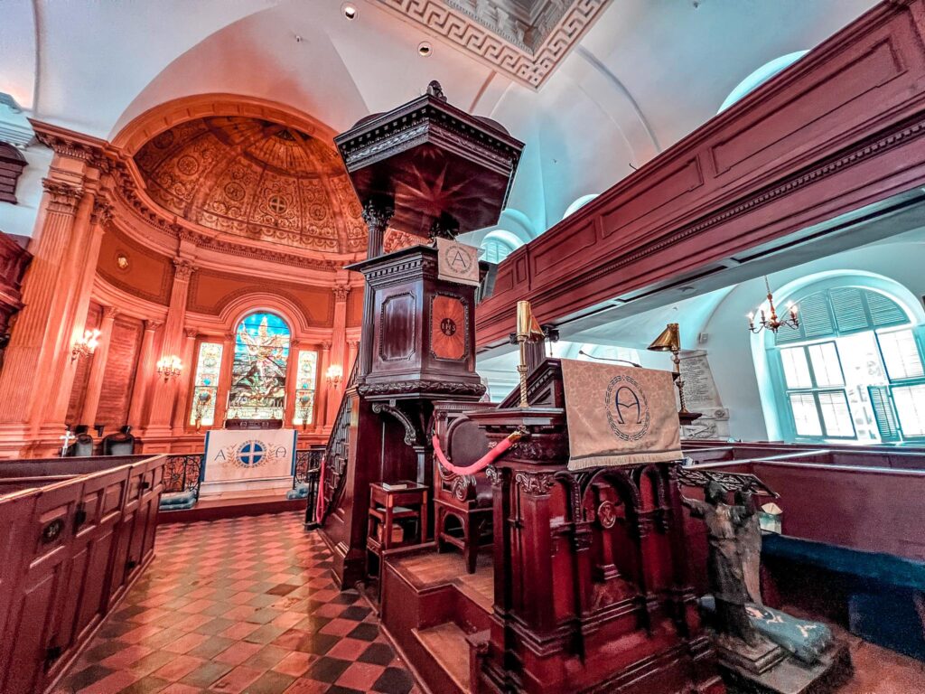 The view of the inside of St. Michael’s Church the oldest church in Charleston, South Caroline and the most famous church in Charleston, SC. The photo features the pulpit and one of the Tiffany windows at the altar. 