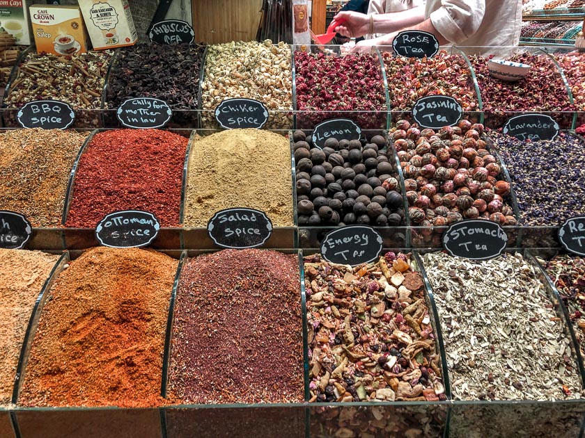 In Istanbul at the Spice Bazaar a vendor has rows and rows of open air spices in square containers of different colours and textures.