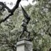 A statue in Oglethorpe Square in Savannah, GA with live oak trees surrounding it with moss. The statue is holding and waving a flag. Seeing the historic squares of Savannah is one of the best things to do in Savannah in one day!